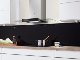 Campana de cocina de chimenea de acero inoxidable sobre un utensilio en una placa de inducción