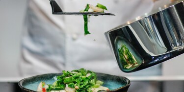 Cocinero emplatando el contenido de una cazuela Infinite Chef