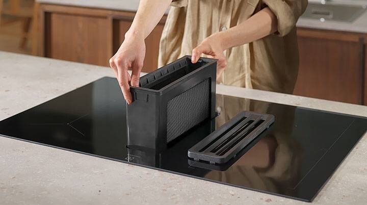 Unas manos recolocando un filtro de grasa en una campana extractora