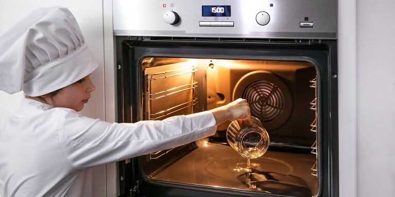 Un minichef vertiendo agua en la cavidad del horno Electrolux PlusSteam